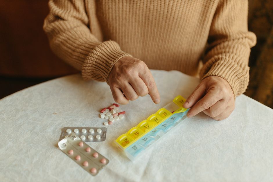 Senior adult organizing weekly medications with a pill organizer, illustrating chronic disease management planning.