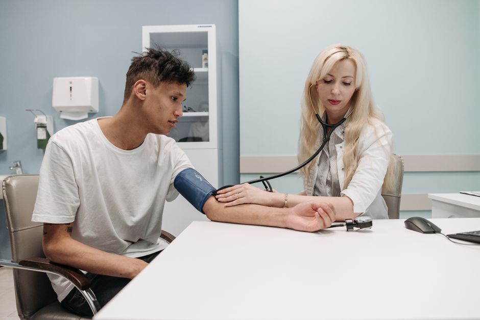 Doctor measuring a patient's blood pressure during a preventive care checkup in a clinic.