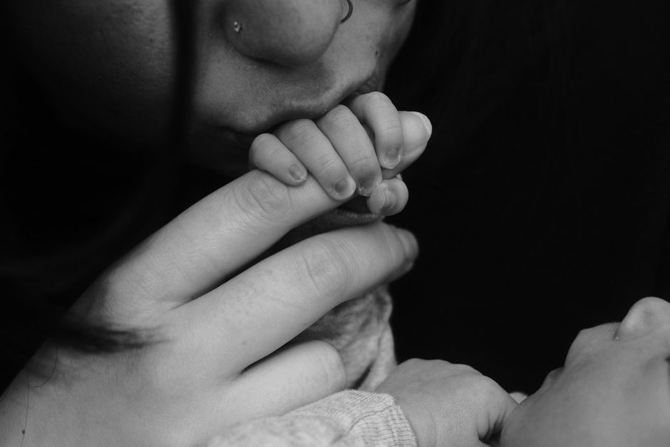 New parent holding baby by a window, looking thoughtful, representing postpartum depression support